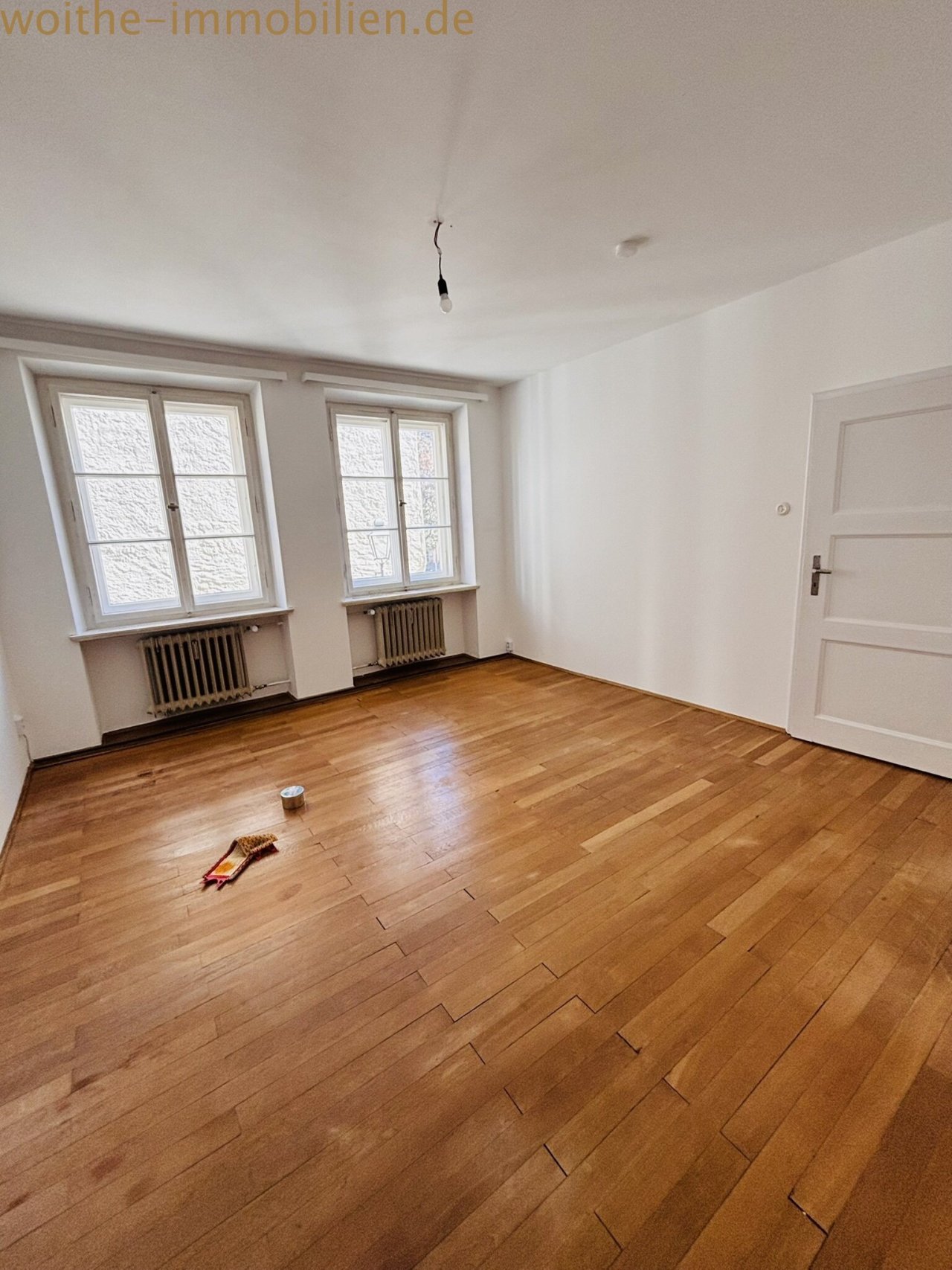 Helles Wohn-oder Schlafzimmer mit edlem Parkettboden in Fischgrätmuster und doppelter Fensterfront – Optimale Lichtverhältnisse und klassische Heizkörper Helles Wohn-oder Schlafzimmer mit edlem Parkettboden in Fischgrätmuster und doppelter Fensterfront – Optimale Lichtverhältnisse und klassische Heizkörper